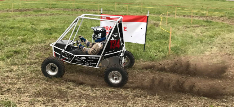 Baja SAE student team member driving car on a course