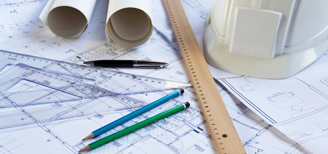 Up close shot of rulers, pens and blueprints on a table